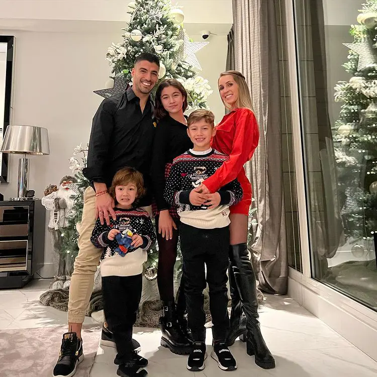 Luis with his wife and three children, posing in front of the Christmas tree.