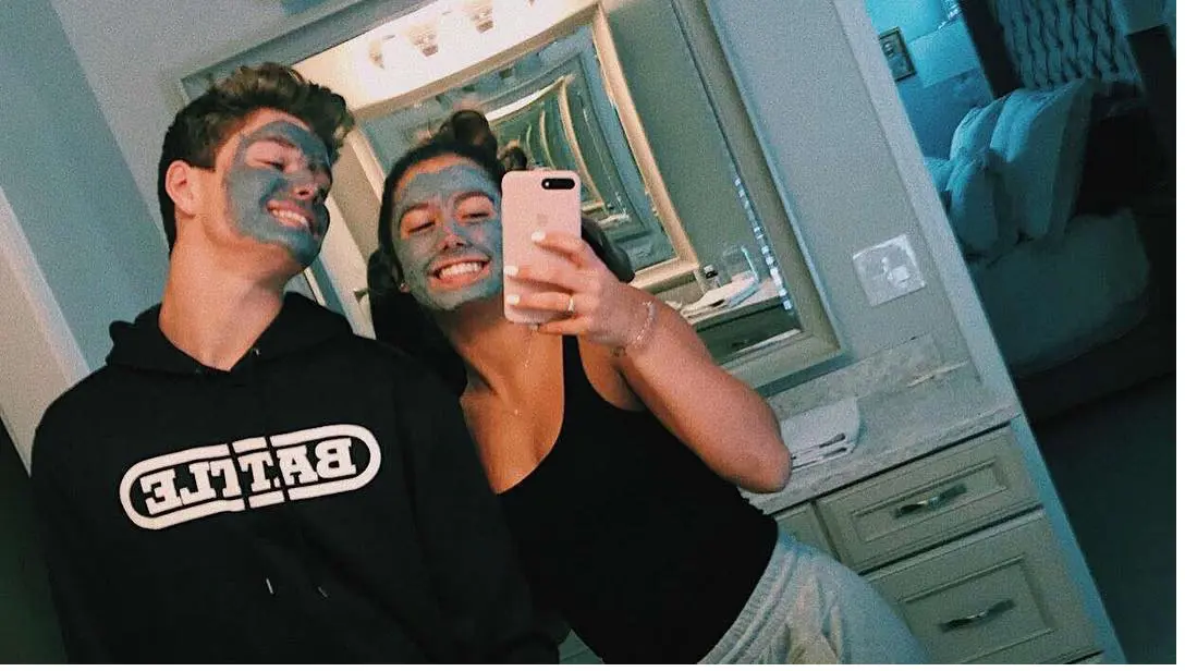 JJ McCarthy poses in a mirror with his girlfriend while wearing a face mask