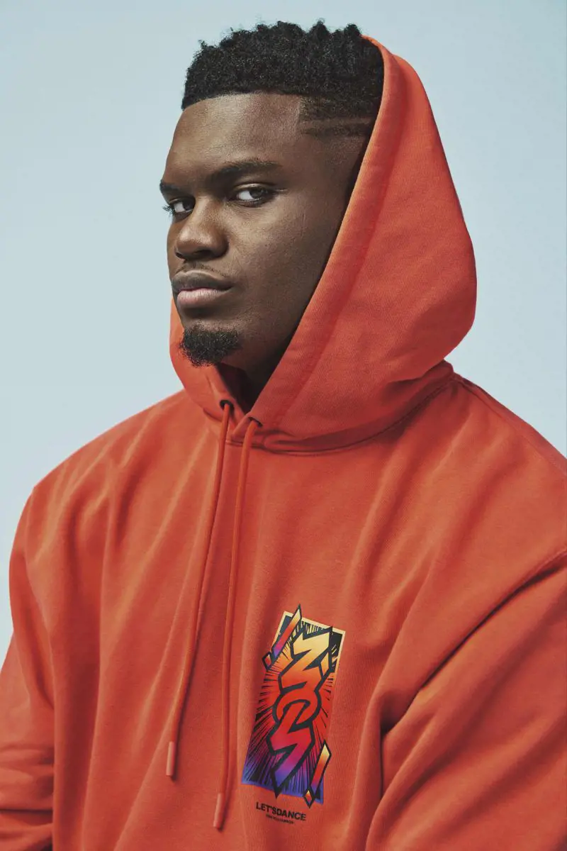 Zion Williamson poses for a photoshoot in an orange drip hoodie