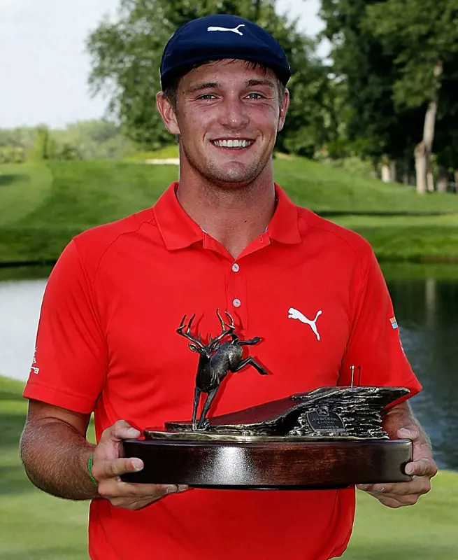 Bryson DeChambeau shows off his John Deere Classic trophy by the pond.