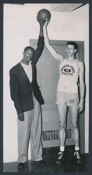 Swede Halbrook and Bill Russell stand side by side comparing their heights and hand reach.